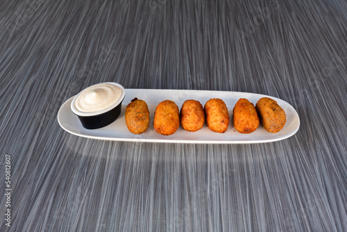 ham croquettes with sauce over a white plate