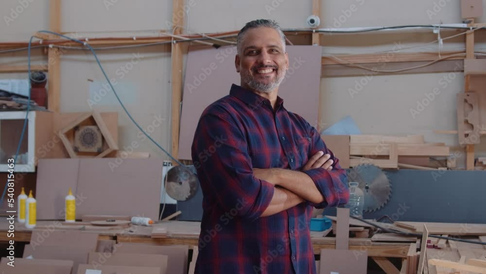 Mid adult man smiling and crossing arms during work at woodworking factory Mid adult man smiling and crossing arms during work at woodworking factory