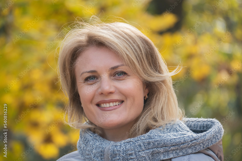 Portrait of a mature woman smiling at the camera at the park. Happy woman. Psychological health, psychology concept. Middle-aged blond woman on a walk in autumn. Portrait of a mature woman smiling at the camera at the park. Happy woman. Psychological health, psychology concept. Middle-aged blond woman on a walk in autumn.