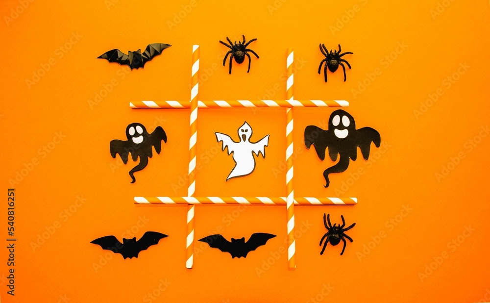 On an orange background, a festive game for Halloween.  Figurines symbols of the holiday lie in a row of black spiders, ghosts and bats.  The concept of entertainment, the development of thinking.