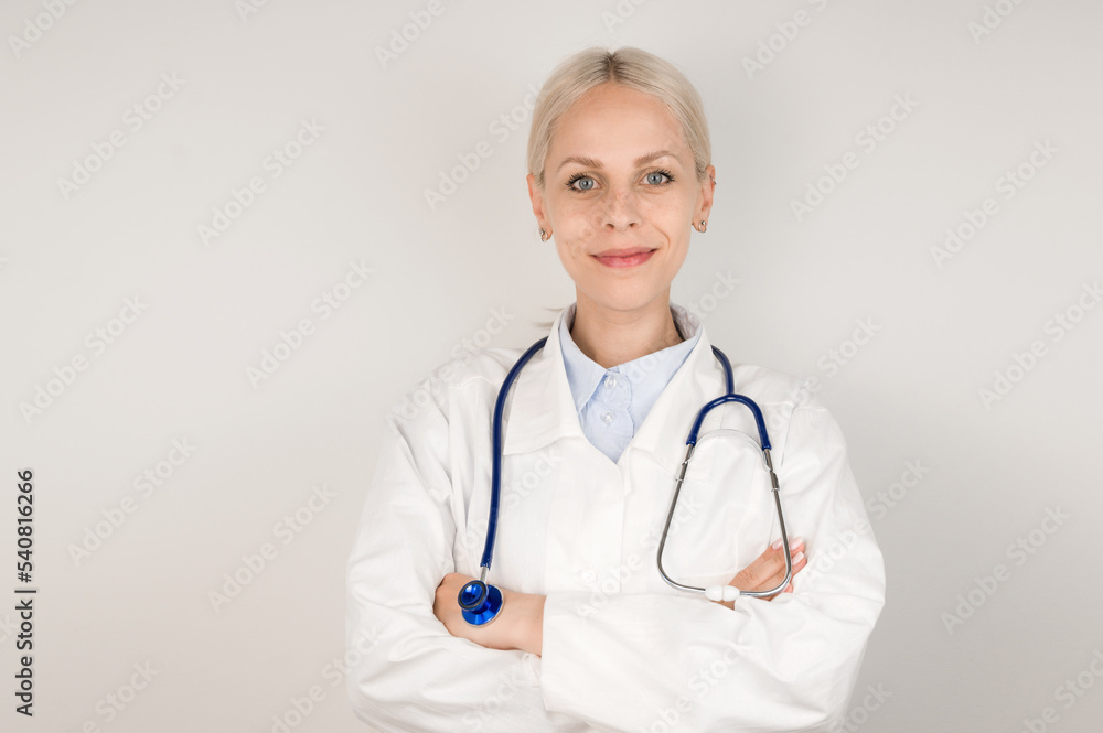 Young blonde doctor standing against gray background smiling at camera. Young blonde doctor standing against gray background smiling at camera.