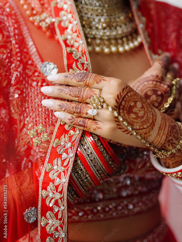 Close-up hands with Mehendi drawings and engagement ring of Indian woman, dressed in traditional red dress