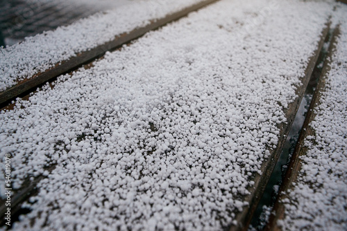 This photo shows many grains of hail on a bench in the city during a thunderstorm. Natural disasters.