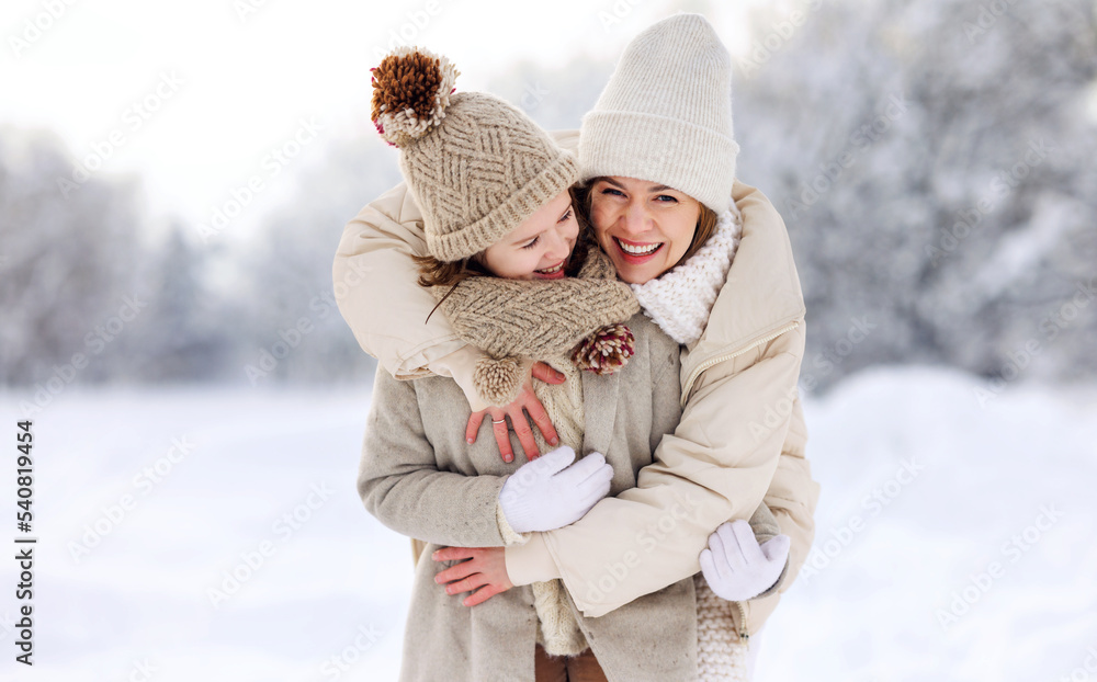 Happy mother embracing little girl daughter while having fun in snowy weather outdoor