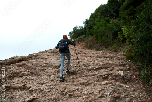 Redhead hiker going up an uneven road