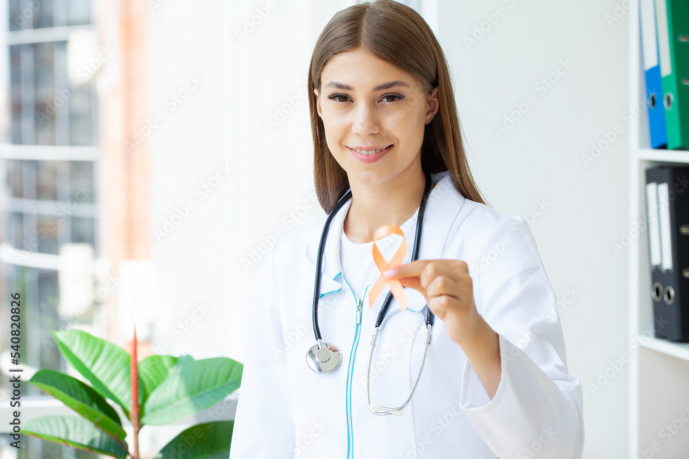 Doctor holding and showing orange awareness ribbon in her hands Doctor holding and showing orange awareness ribbon in her hands