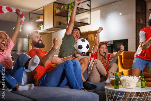 Фотография Football fans cheering while watching the game on TV at home