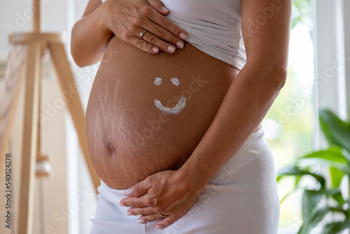 Smiley drawn with cream on pregnant belly photo