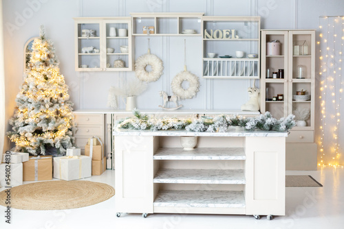 Christmas decorated light kithen. Pastel white and beige colors. Modern stylish interior of kitchen decorated for New Year Eve. Christmas morning © Olga Mishyna