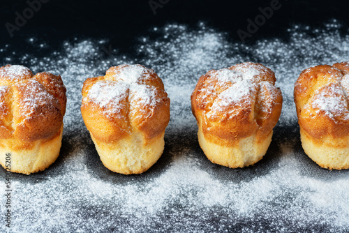 Muffins with white powdered sugar on black background