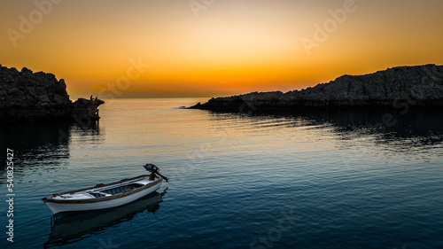 Lonely boat in sunset / sunrise on a sea in Lindos bay, Rhodes, Greece