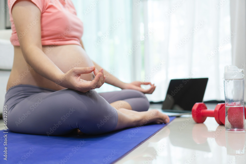 Healthy Asian pregnant woman doing yoga exercise in lotus position