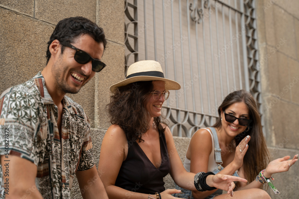 Obraz premium a group of three friends having fun and laughing on a bench in the street