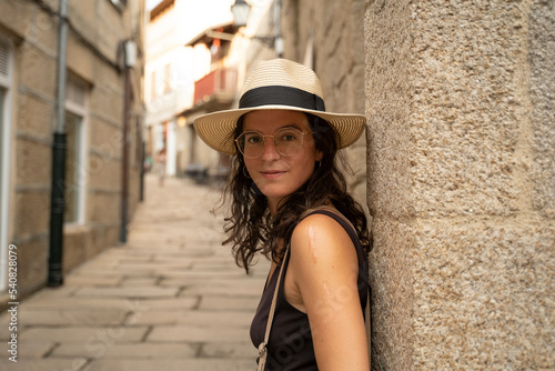 Beautiful young caucasic woman with a hat smiling to the camera in the streets of Spain
