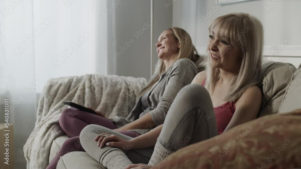 Women sitting on sofa watching television and laughing / Cedar Hills, Utah, United States Women sitting on sofa watching television and laughing / Cedar Hills, Utah, United States