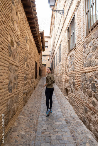 Young woman traveller walking through a narrow street during a antumn afternoon. © Otávio Pires