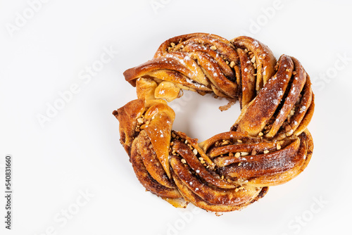 Roscón de reyes Kringle Estonia. Typical Christmas sweet, braided sponge cake with cinnamon, butter, walnuts or almonds and icing sugar on a white background.