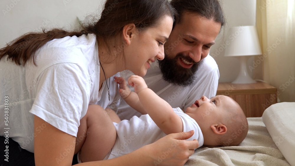 Woman And Man Holding Newborn. Mom, Dad And Baby On Bed. Close-up. Portrait of Young Smiling Family With Newborn On Hands. Happy Marriage Couple On Background. Childhood, Parenthood, Infants Concept Woman And Man Holding Newborn. Mom, Dad And Baby On Bed. Close-up. Portrait of Young Smiling Family With Newborn On Hands. Happy Marriage Couple On Background. Childhood, Parenthood, Infants Concept