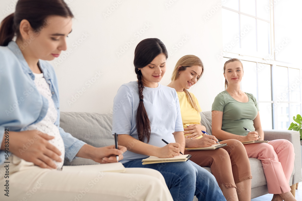 Young pregnant women writing in notebooks at course for expectant mothers Young pregnant women writing in notebooks at course for expectant mothers