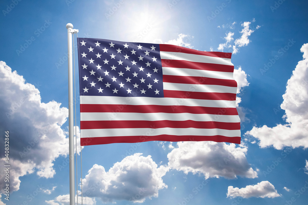 USA flag on a flagpole waving in the wind on a sunny blue sky background. Flag of United States of America USA flag on a flagpole waving in the wind on a sunny blue sky background. Flag of United States of America