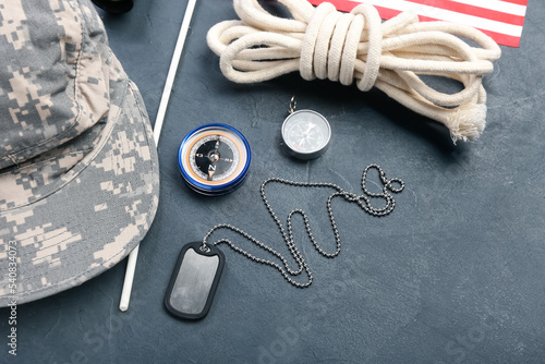 Military tag, compasses, rope and cap on dark background