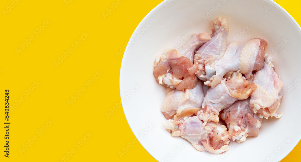 Fresh raw chicken wings (wingstick) in white bowl on yellow background.