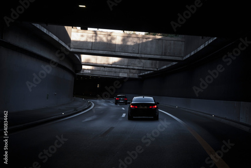 Obraz na płótnie Black car is driving down the road in the tunnel. Traffic infrastructure, tunnel architecture, light effect. w salonie