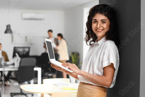 Young businesswoman working with laptop during meeting in office