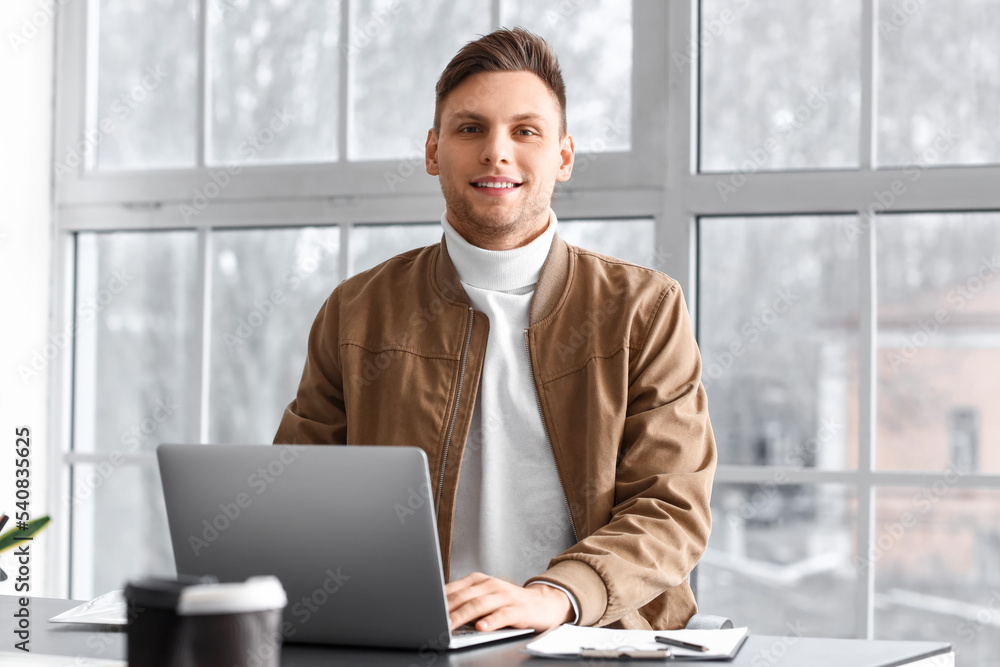 Smiling businessman working with laptop at table in office Smiling businessman working with laptop at table in office