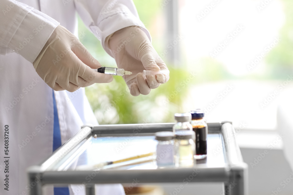 Female doctor with syringe near table in clinic, closeup Female doctor with syringe near table in clinic, closeup