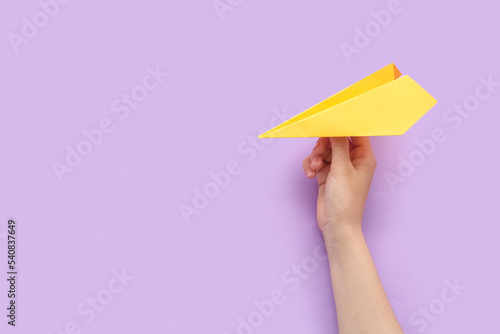 Woman with yellow paper plane on lilac background