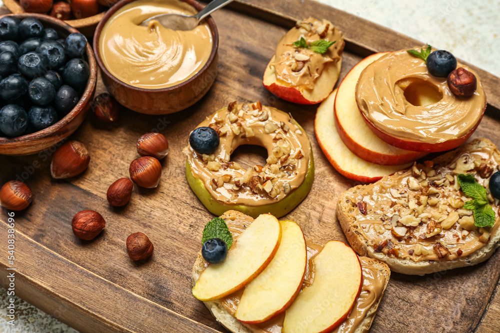 Wooden board of tasty sandwiches and apple rounds with nut butter, closeup Wooden board of tasty sandwiches and apple rounds with nut butter, closeup