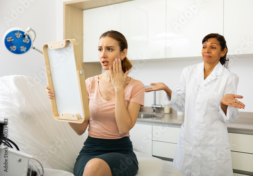 Portrait of unhappy worried woman after cosmetological procedure at clinic of esthetic medicine photo