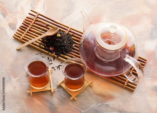 Glass cups and teapot of hot black tea on grunge background