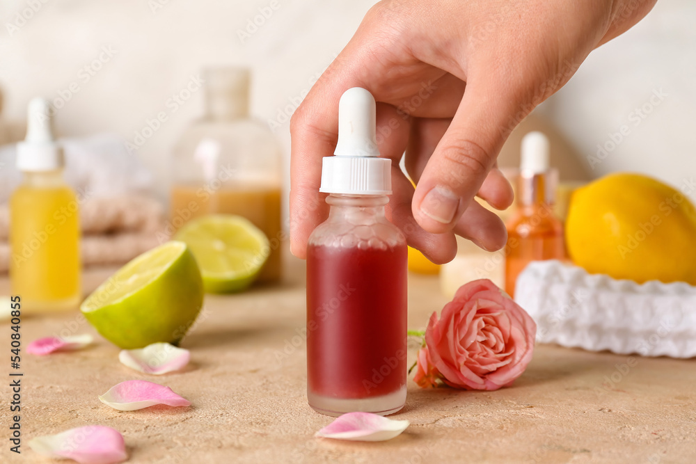 Female hand with bottle of vitamin C serum on table, closeup Female hand with bottle of vitamin C serum on table, closeup