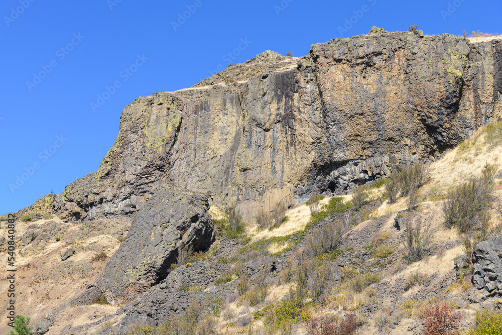 Basalt cliff face rises above a dry slope in Central Washington