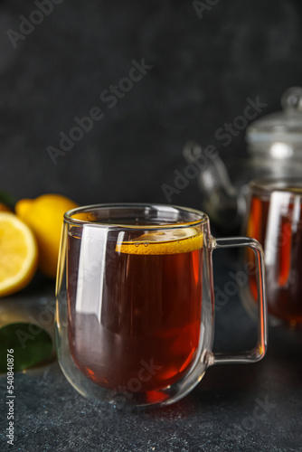 Glass cup of black tea with lemon on dark background, closeup