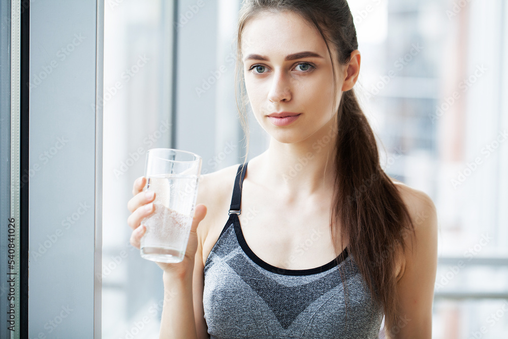 Smiling pretty woman holds a glass of water leaning Smiling pretty woman holds a glass of water leaning
