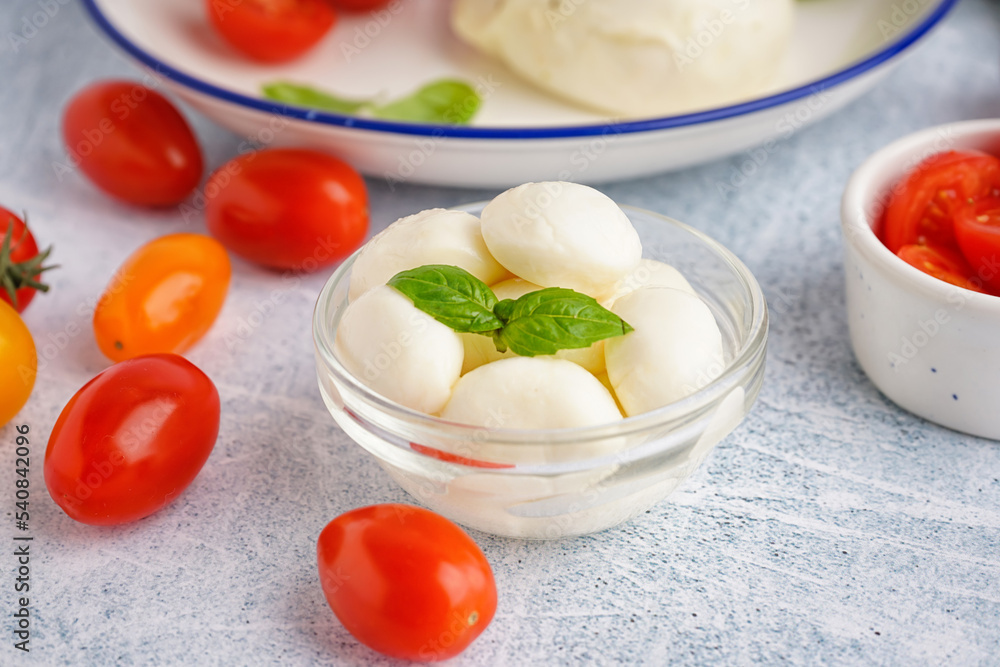 Bowl of delicious mozzarella cheese and tomatoes on light background Bowl of delicious mozzarella cheese and tomatoes on light background