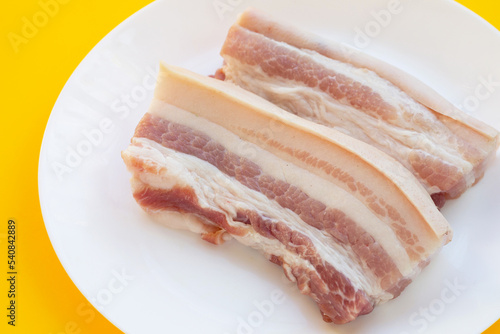 Streaky pork in white plate on yellow background.