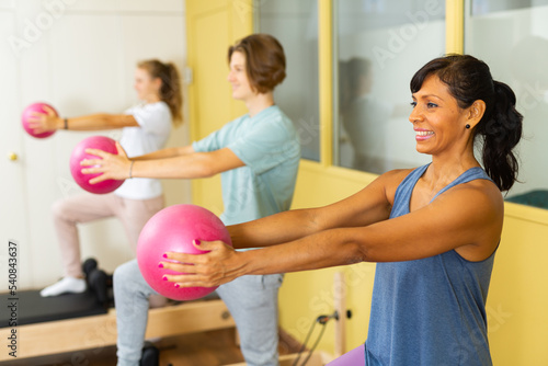 Positive woman pilates instructor with teenagers engaged in gym