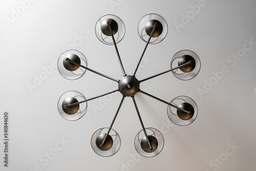 A round chandelier of several lamps against a light ceiling, full frame, bottom view