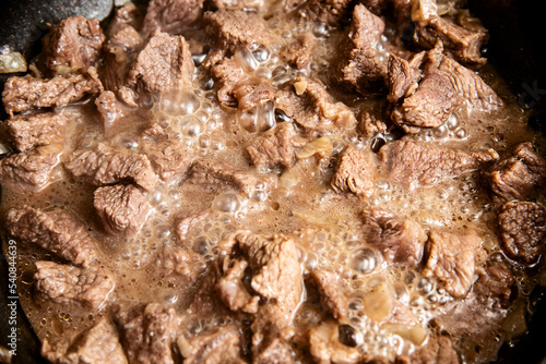 close-up beautiful large pieces of fried meat with onions in a pan