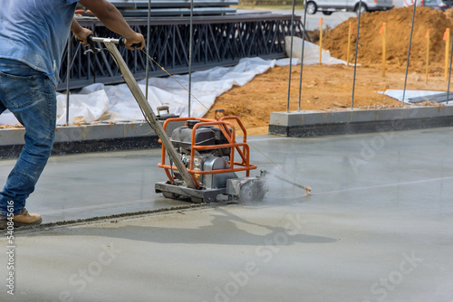 Worker using cutting machine are cutting concrete for expansion isolation joint of foundation concrete after pouring in construction site