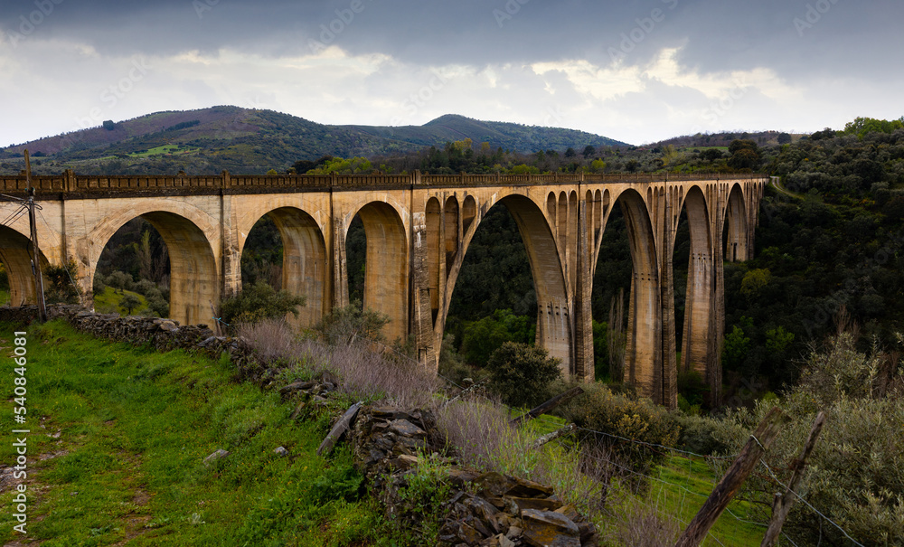 Impressive view of old railway bridge Viaduct of Guadalupe, Spain, at cloudy spring day