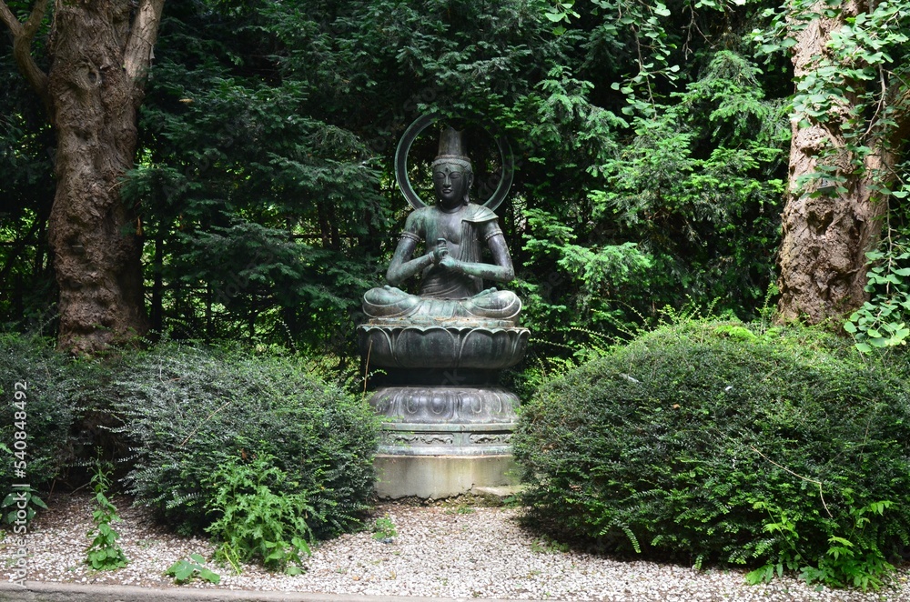 Bronze statue in park among green vegetation