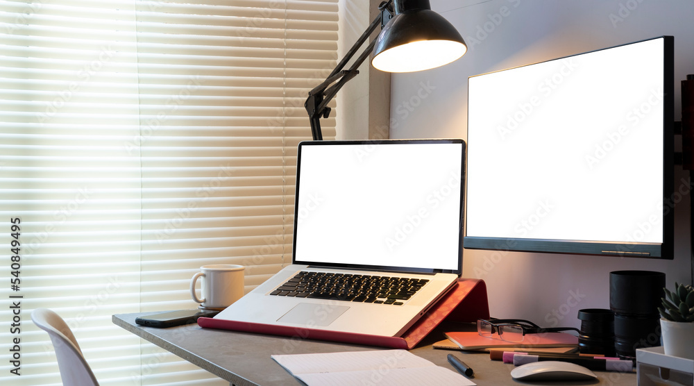 Modern workplace with white blank computer screen, laptop and supplies on black table. Modern workplace with white blank computer screen, laptop and supplies on black table.