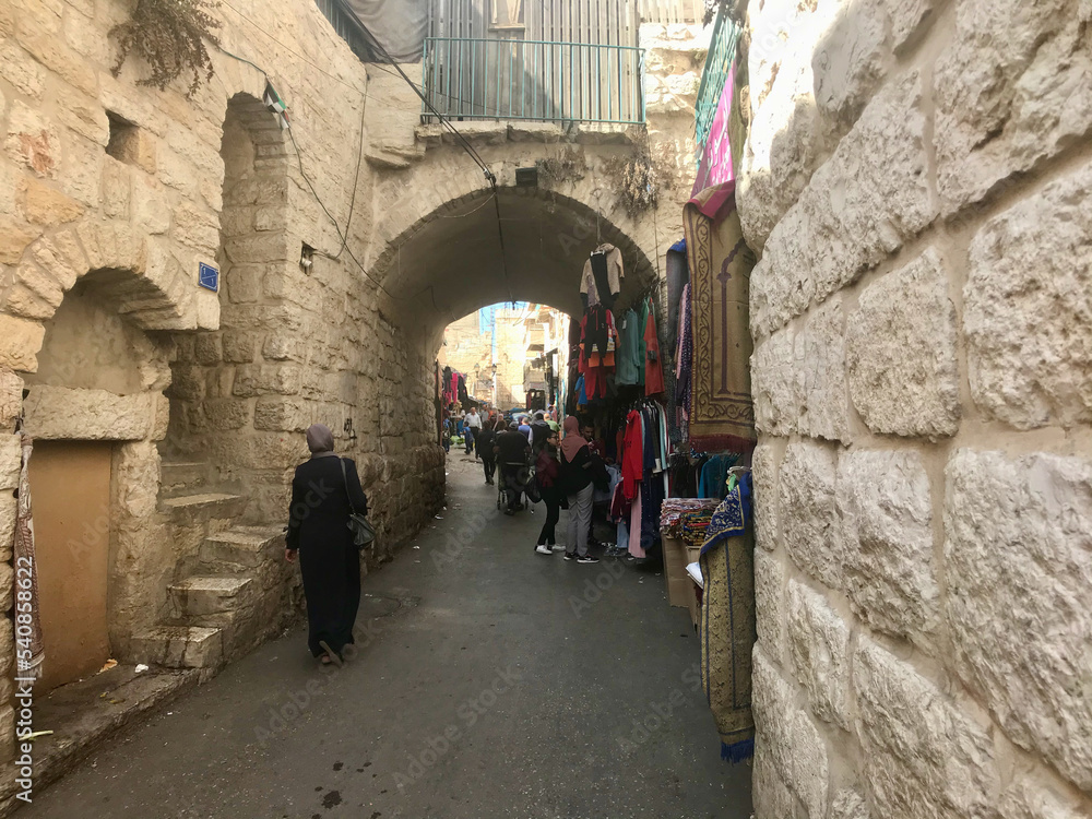 Bethlehem, Palestine, November 2019 - A group of people walking down a street next to a stone wall
