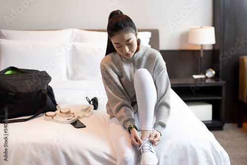 Young woman tying her shoelaces in bedroom