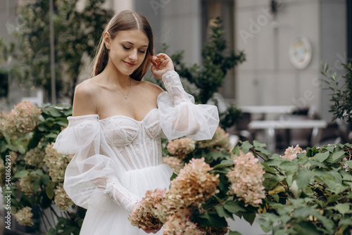 Photos Attractive woman wearing wedding dress admiring flowers.